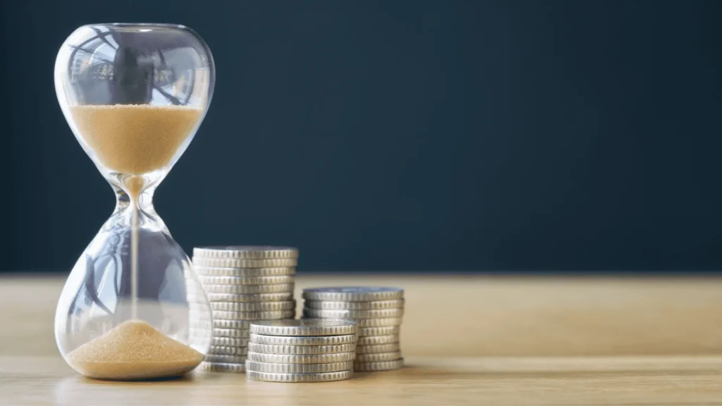 Hourglass next to stacks of coins, symbolizing fast cash flow, accelerated collections, and time-saving back office support