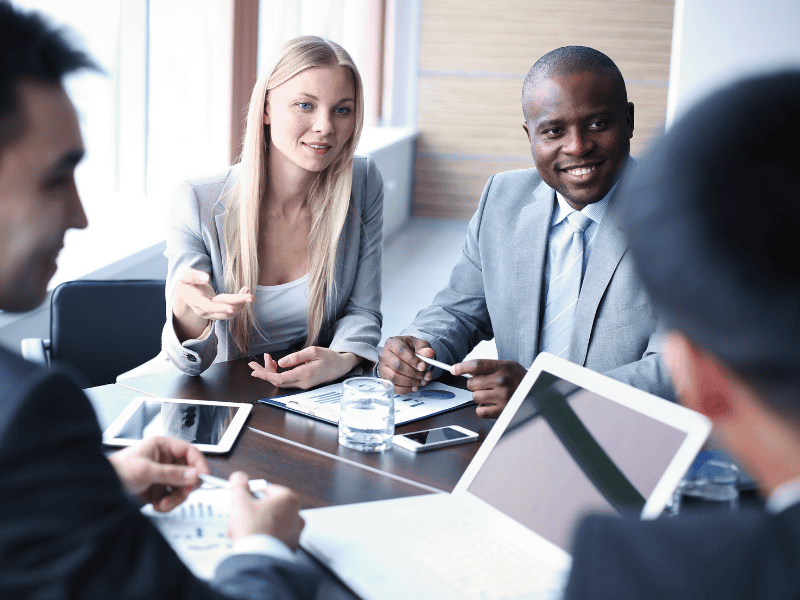 Two business professionals discussing financial reports and negotiating terms, symbolizing expert claims follow-up and negotiation support with insurance carriers