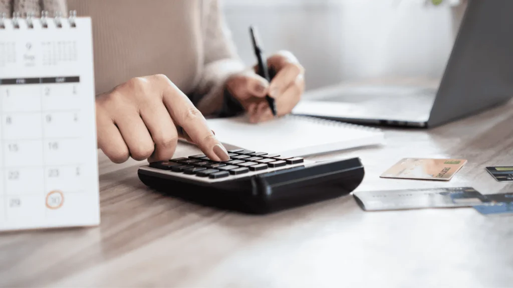Close-up of hands using a calculator and notebook to accurately estimate restoration costs, avoiding common financial mistakes.