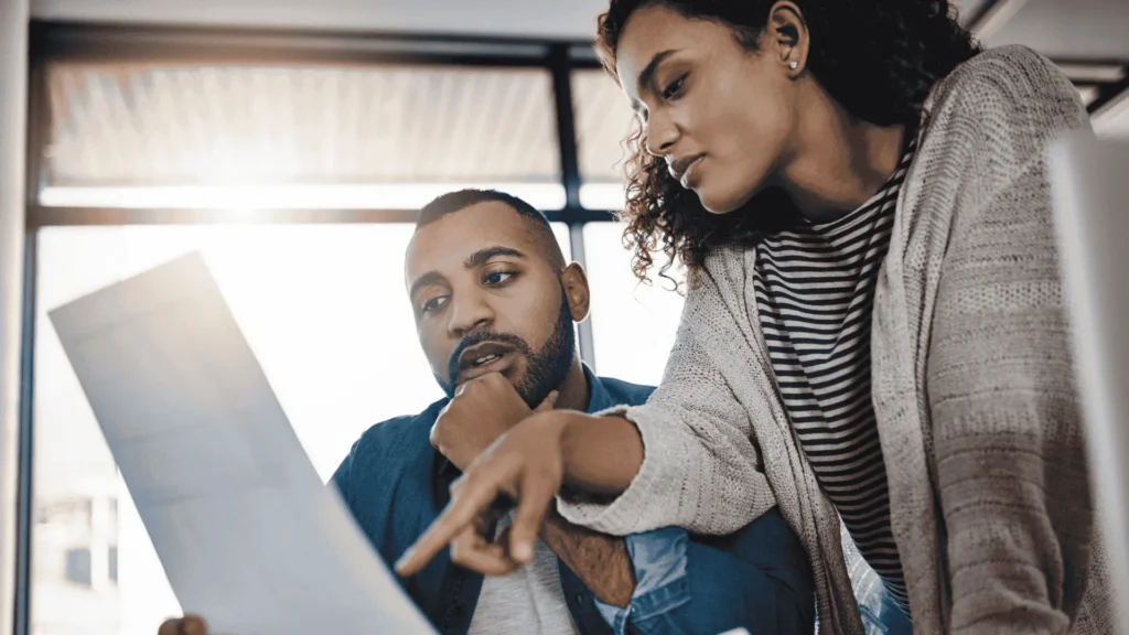Two business professionals analyzing a complex insurance policy document to spot exclusions and limits for a property claim