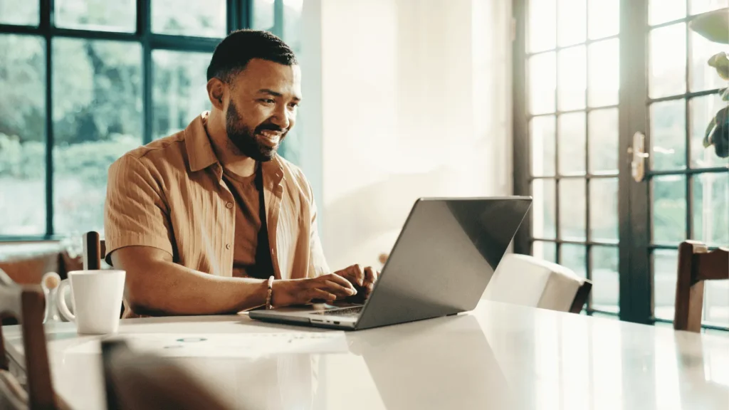 A smiling professional contractor typing a polite follow-up email on a laptop in a bright office, illustrating the difference between effective communication and aggressive collections.