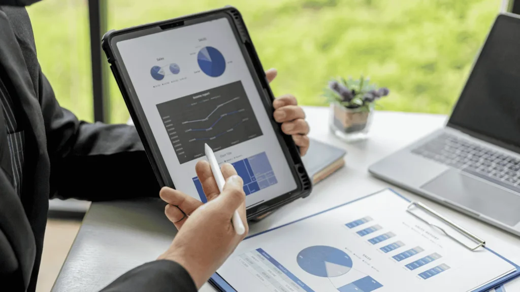 A professional using a stylus on a tablet to analyze digital charts and graphs, comparing data accuracy between Xactimate and other estimating tools.